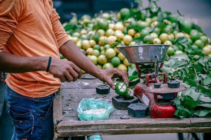 Een handelaar weegt fruit af op een marktkraam