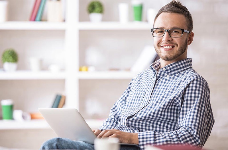 Een lachende medewerker met een laptop