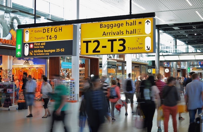Reizigers onder de borden naar de gates op een luchthaven